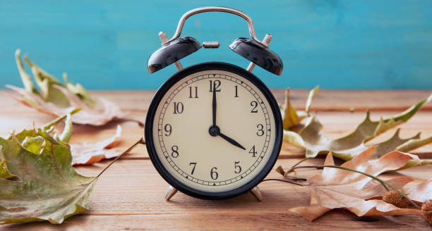 istock Fall Back Daylight Saving Time. Black clock and autumn leaves on wood 1433040765