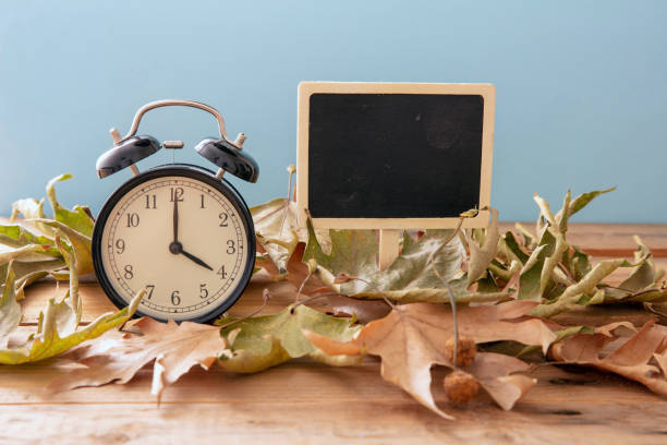 istock Fall Back Daylight Saving Time. Black clock and autumn leaves on wood 1433040769