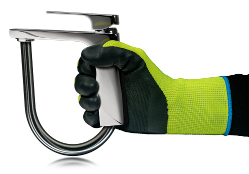 Plumber with a green and black protective work gloves, holding a chrome water faucet and a water pipe, isolated on white background. Water saving concept.