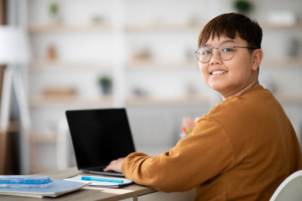 fröhliches chinesisches kind mit laptop mit leerem bildschirm - teen obesity stock-fotos und bilder