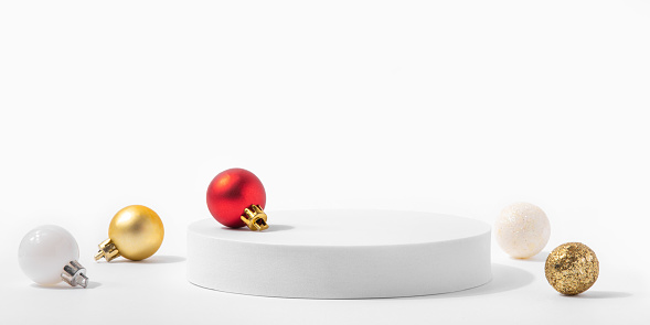 Cosmetic background for Christmas and winter holiday. White podium and christmas balls on white background.