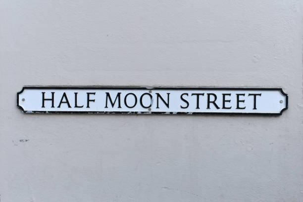 close up of street name plate,  Half Moon Street, on an old grey painted wall background. close up of street name plate,  Half Moon Street, on an old grey painted wall background.  The vintage text sign is written in black on a white metal background. street name sign stock pictures, royalty-free photos & images