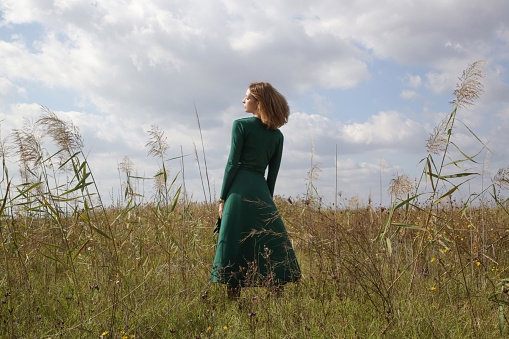 Serie of photos of female model in green dress posing on meadow. Outdoor portrait with natural light.