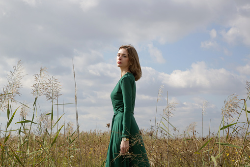 Serie of photos of female model in green dress posing on meadow. Outdoor portrait with natural light.