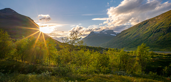 Sun setting behind the mountain in remote Arctic valley. Sarek National Park, Lapland, Sweden. Sun star. Hiking in remote wilderness of Laponia. Sunset in the mountains