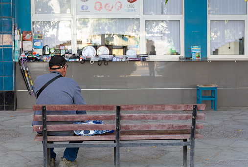 Kazakhstan, Shymkent October 11, 2022:\n  an elderly man sits resting on a bench and erases on his watch