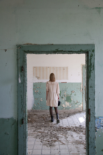 Serie of photos of female model in beige dress in the abandoned ruined building