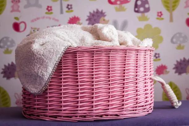 Decorative knitted pink laundry basket with white blanket