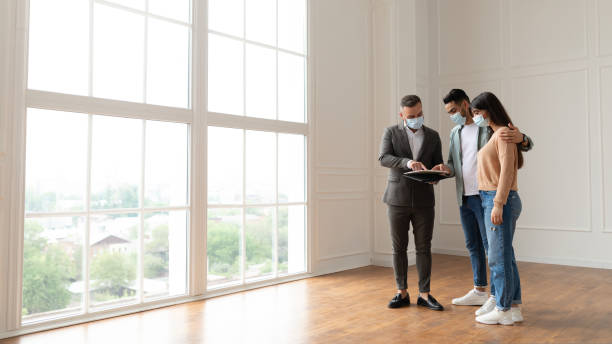 istock Couple In Facemask Buying New Apartment, House Agent Showing Documents 1433059033