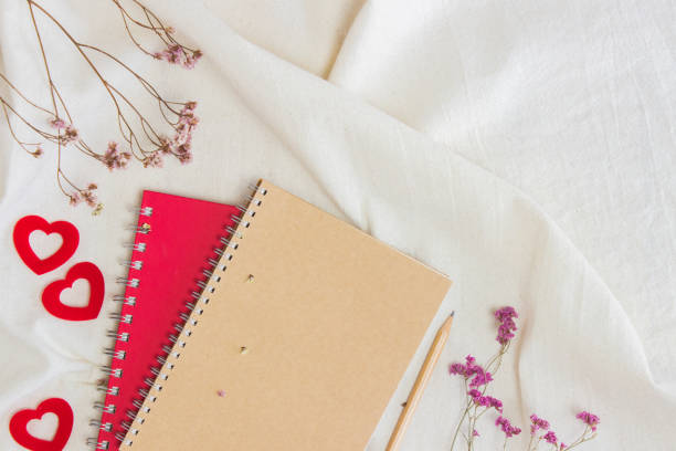 istock Brown and red notebooks with red flowers on white fabric. 1433060095