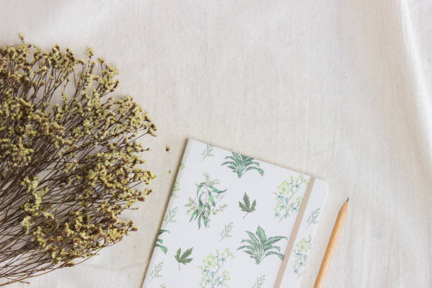 istock Yellow flowers with notebook and pencil over the white fabric. 1433060098