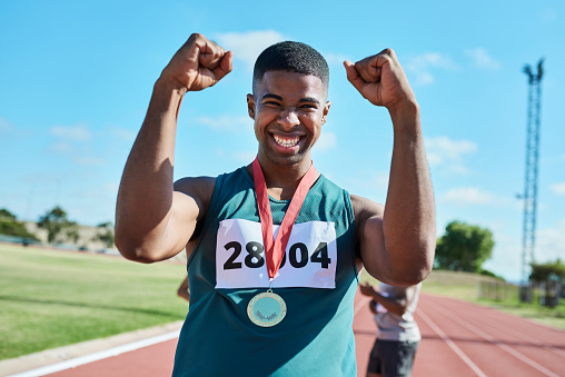 Celebration, athlete and winner at running marathon on sports track celebrating success. Sport, exercise and portrait of a happy runner with a smile to celebrate his victory, achievement and winning.