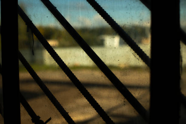 Grille on window. Steel grating. Old window inside view. Interior details. Dirty glass.