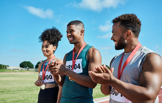 Race, winner and sport athlete medal applause of sports people on a outdoor track. Happy black people with celebration and winning motivation achievement mindset smile about runner fitness win
