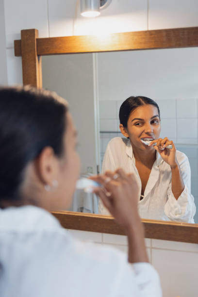 istock Woman brushing teeth and looking in mirror at home 1433064324