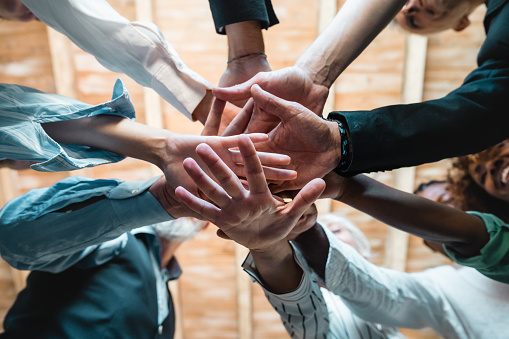 Group of businesspeople joining hands together standing in circle, closeup view from bottom - Creative business teamwork building concept - soft skills project