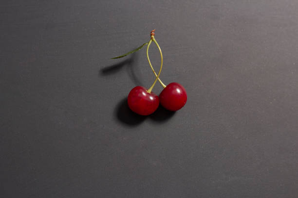 dos cerezas rojas, dulces y jugosas resaltadas sobre un primer plano de fondo negro - sour cherry cherry sour taste cute fotografías e imágenes de stock