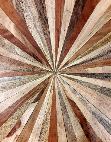 Inlaid wooden tabletop with starburst rays or sun star shape design. Dynamic dramatic marquetry. Symmetrical abstract pattern and texture.