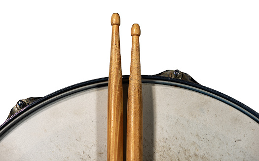 Close-up of two wooden drumsticks and an old metallic snare drum, isolated on white background, photography. Percussion instrument.