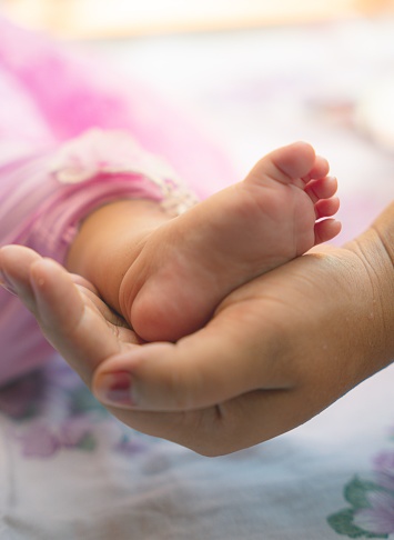 A newborn baby foot in mother's hand,vertical shot