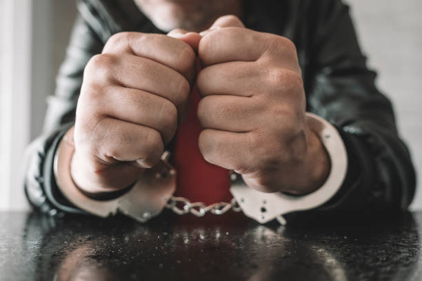 handcuffed hand is strapped inside interrogation room. concept of arrest and incarceration. A prisoner in prison. interrogation in prison. criminal is being interrogated. conducting interrogations