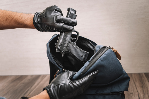 A man in gloves takes a gun out of his backpack. Seizure of weapons and baggage search. Crime concept. The policeman searches the bag. evidence of a crime.