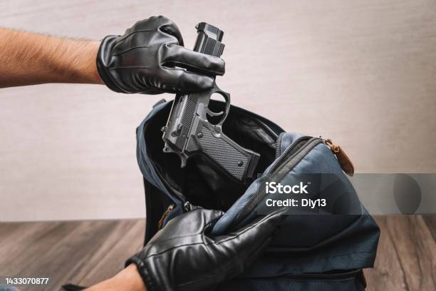 Man In Gloves Takes A Gun Out Of His Backpack Seizure Of Weapons And Baggage Search Crime Concept The Policeman Searches The Bag Evidence Of A Crime Stock Photo - Download Image Now