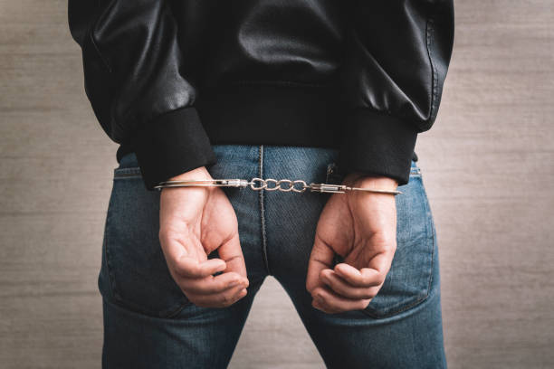 istock Arrested man handcuffed hands at back. prisoner concept, Handcuffed hands of a prisoner in prison, Male prisoners were severely strained in the dark prison, violence, handcuffed hands is strapped 1433070890