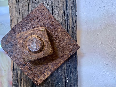 Horizontal close up of rusted rustic metal antique nut and bolt on wood railway sleeper rail plank