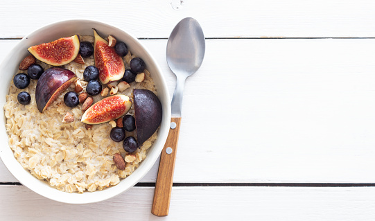 Oatmeal porridge with figs, blueberries, almonds and honey. Healthy eating. Vegetarian food.