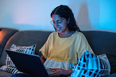 Happy Young Hispanic Female Is Browsing On Her Computer And Sitting On The Sofa