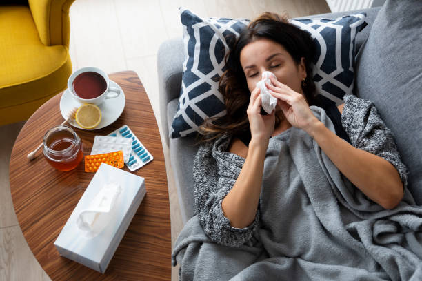 istock Sick woman blows her nose, lying on bed 1433074045