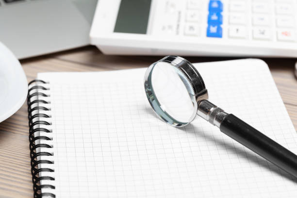 istock Magnifying glass and notebook on wooden table 1433076085
