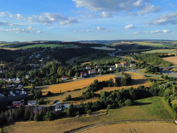 istock Drone shot over forested mountains and a village surrounded by green fields 1433077069
