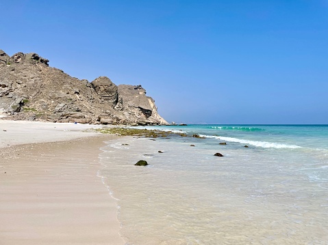 The rocky sea-cliff at Fazayah Beach under blue sky in Salalah, Oman