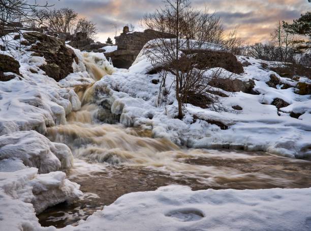 istock Low exposure of water flowing down the rocks covered in snow. 1433080658