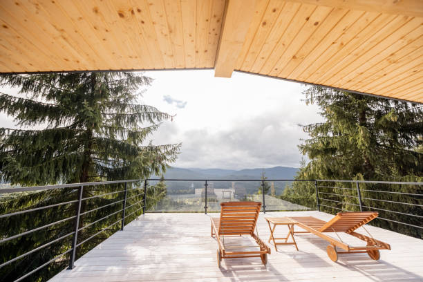 Spacious terrace with wooden lounge beds on nature with scenic view on pine trees and mountains