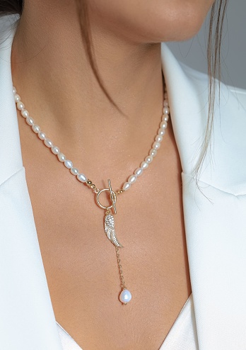 A closeup shot of a key pearl necklace worn by a Caucasian female.