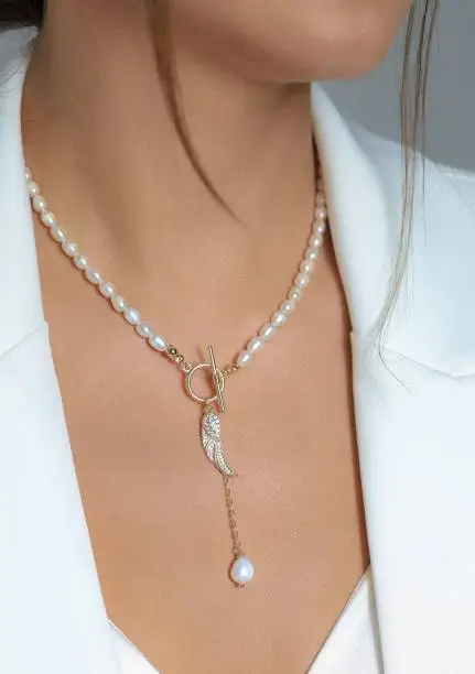 Photo of Closeup shot of a key pearl necklace worn by a Caucasian female.