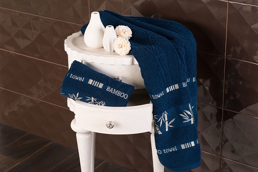 A closeup shot of a bathroom cabine with a drawer with navy blue bamboo towels