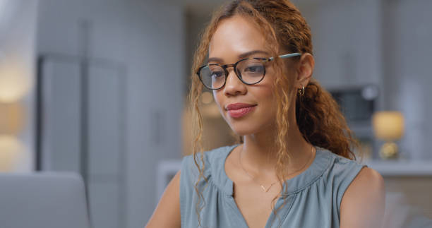 istock Corporate freelancer with glasses working on a laptop at a table doing research in her living room. Professional employee with a remote job planning a creative project with computer at home. 1433085026