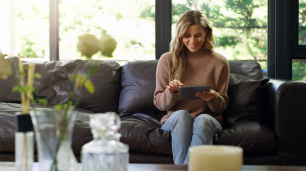 istock Happy, social media and woman with digital tablet on sofa browsing, internet and communication at home. White blond female in living room in happiness on couch with touchscreen technology on the web 1433086801
