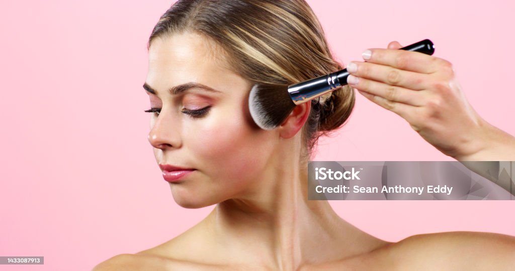 Face makeup, cosmetic beauty and woman with cosmetics foundation, facial powder and brush for glow against pink mockup studio background. Model with natural, organic and clean product for body Foundation Make-Up Stock Photo