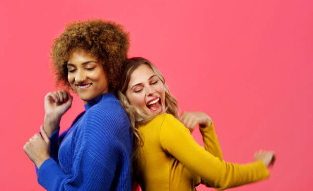 istock Friends together and dancing with a studio background for fun comedy moment while they bond. Comic, happy and funny women enjoy playful humor while they spend time with each other. 1433087936