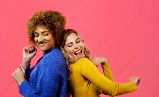 Friends together and dancing with a studio background for fun comedy moment while they bond. Comic, happy and funny women enjoy playful humor while they spend time with each other.