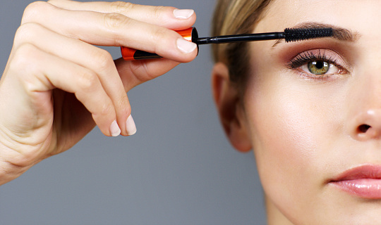 Beauty makeup. Woman shaping eyebrow with brow pencil closeup. Girl model with professional makeup contouring eyebrows
