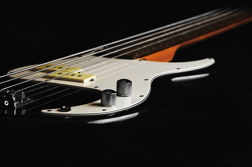 A closeup of a white electric guitar against a black background