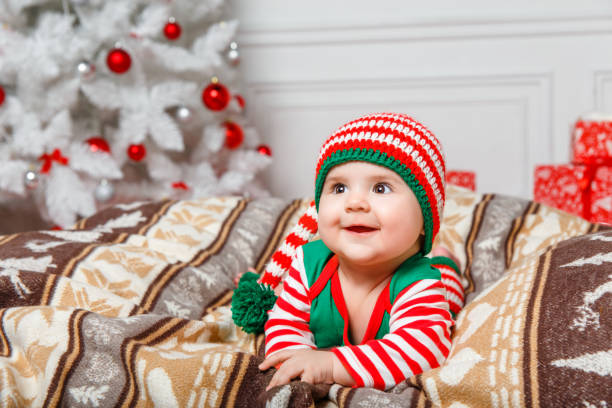Toddler boy in elf costume for Christmas on windowsill.