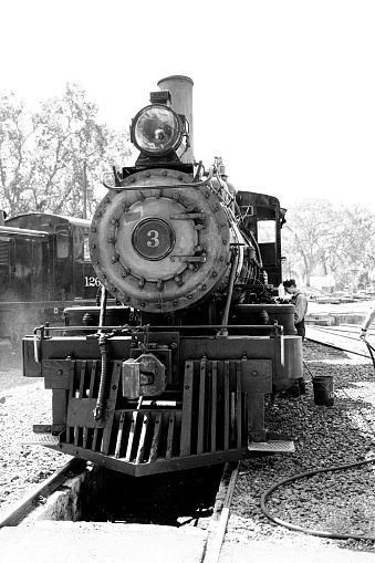 A vertical grayscale shot of an old train on the railroads of Jamestown, California