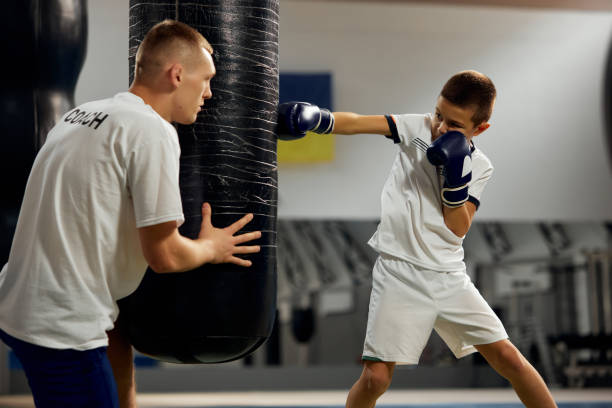 istock School age boy, beginner boxer practicing punches with personal coach at sports gym, indoors. Concept of studying, challenges, sport, hobbies, competition 1433091400